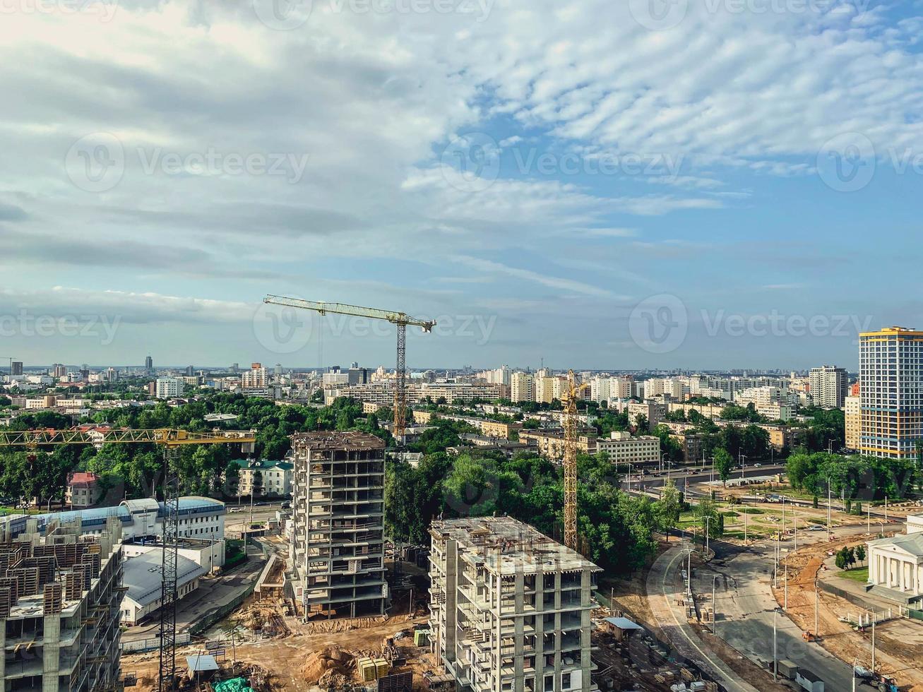 costruzione di multipiano edifici nel il città centro. alto case fatto di calcestruzzo blocchi e lastre. un' gru erige edificio Materiale su contro un' blu, chiaro cielo foto