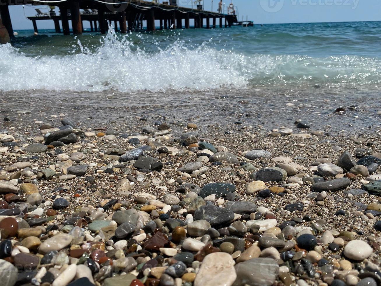 piccolo ciottoli su il costa. soleggiato estate giorno blu cielo, bianco nuvole. bellissimo solitario piccolo ciottolo spiaggia.copia spazio foto