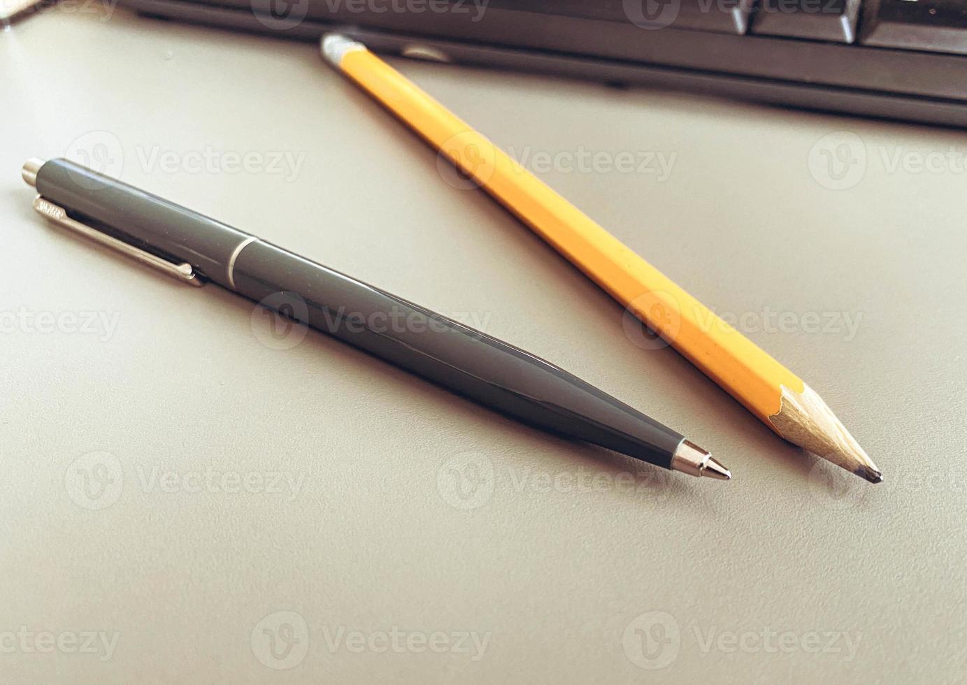 Stazionario su il tavolo nel il ufficio. un' blu metallo penna per scrivere, un' semplice di legno matita con piombo. carta scrittura attrezzo foto
