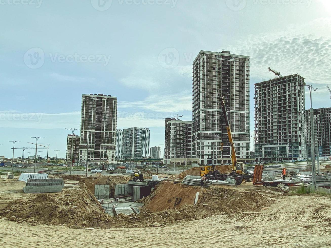 costruzione di un' nuovo Quartiere nel il città. erezione di alto, multipiano edifici fatto di calcestruzzo, bicchiere, blocchi. scavando un' fondazione fossa nelle vicinanze foto