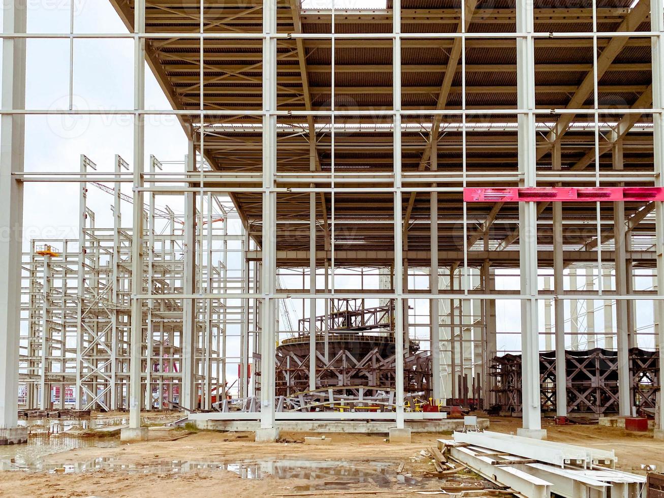 costruzione di un' nuovo complesso a il pianta. metallo strutture per il costruzione di un' nuovo costruzione. edificio Materiale è coperto con ruggine e bugie nel un' pozzanghera di acqua foto