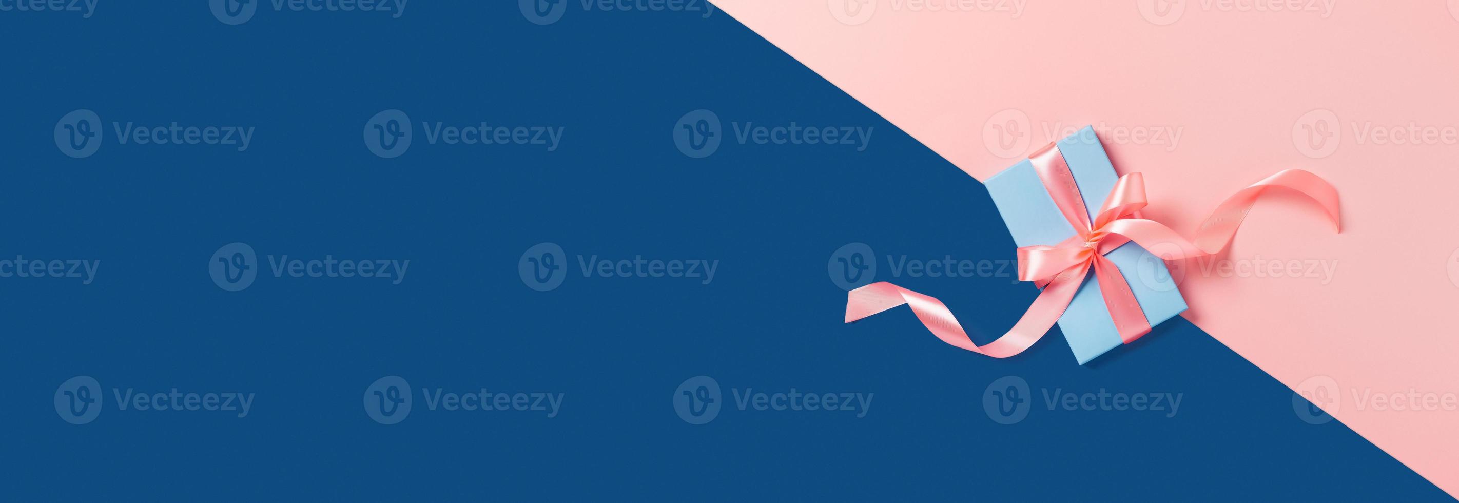 vacanza web-banner. un' blu scatola con un' rosa arco su bicolore sfondo. foto