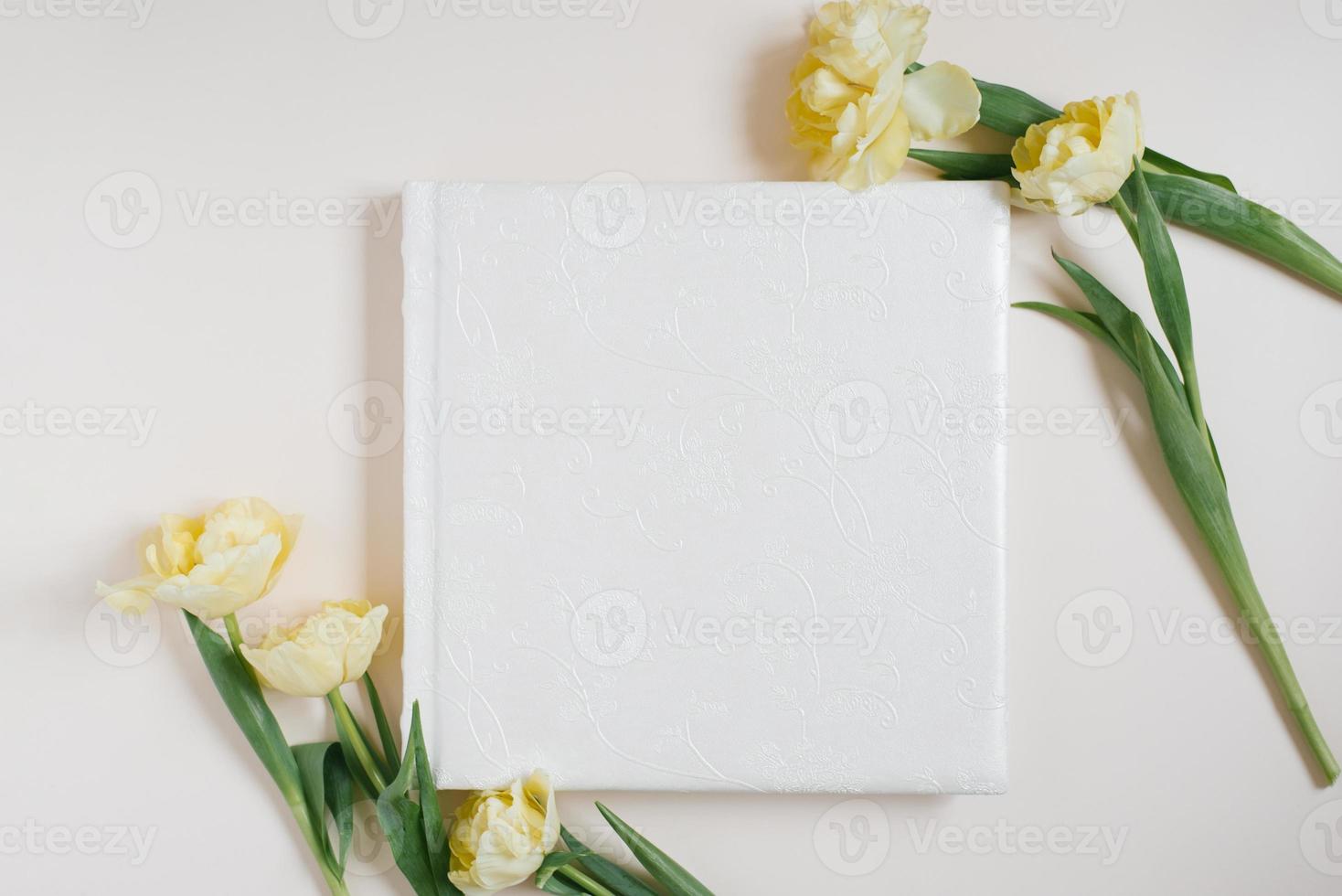 composizione con un' nozze o famiglia foto album, un' mazzo di fiori di giallo tulipani su un' leggero sfondo. piatto posizione, superiore Visualizza ancora vita.