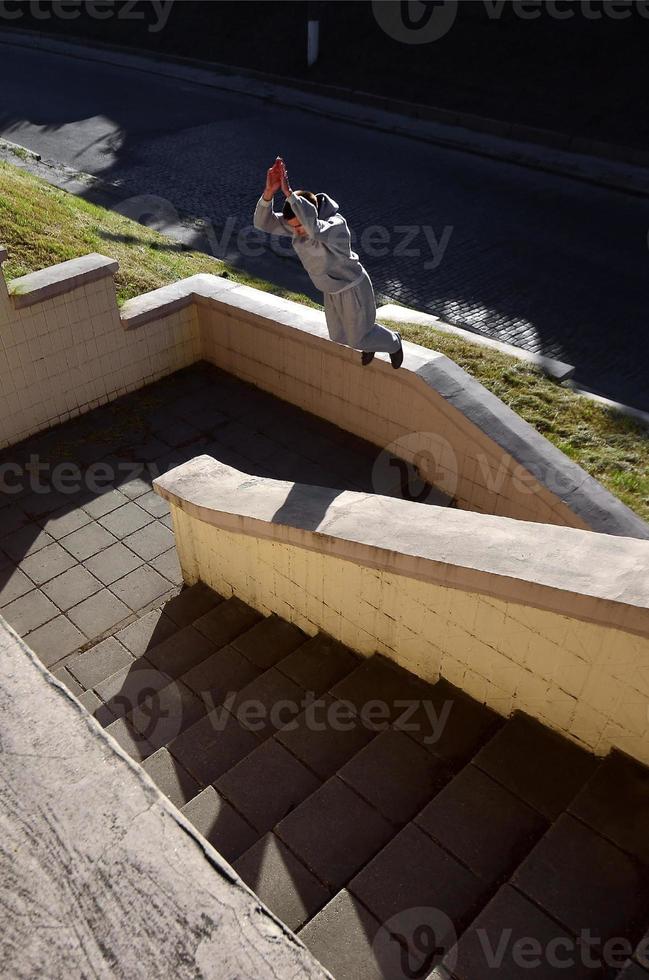 un' giovane tipo esegue un' saltare attraverso il spazio fra il calcestruzzo parapetti. il atleta pratiche parkour, formazione nel strada condizioni. il concetto di gli sport sottoculture tra gioventù foto