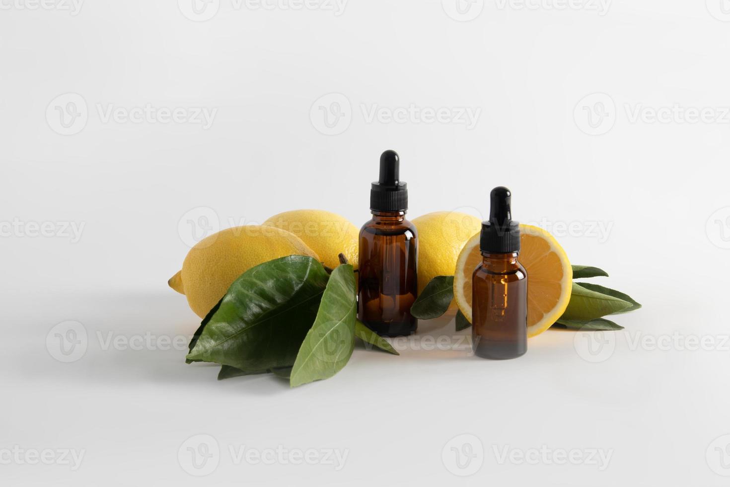 Due cosmetico bottiglie con un' pipetta con un' siero basato su Limone essenziale olio su un' bianca sfondo con maturo frutta. ringiovanente effetto. vitamina c. foto