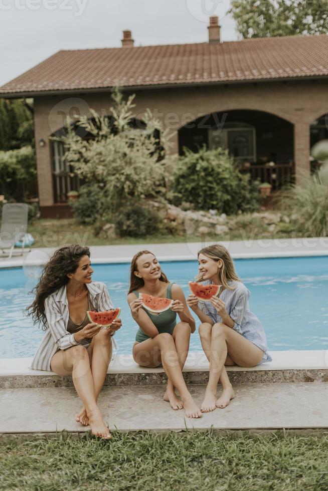 giovane donna seduta su di il nuoto piscina e mangiare anguria nel il Casa Giardino dietro la casa foto