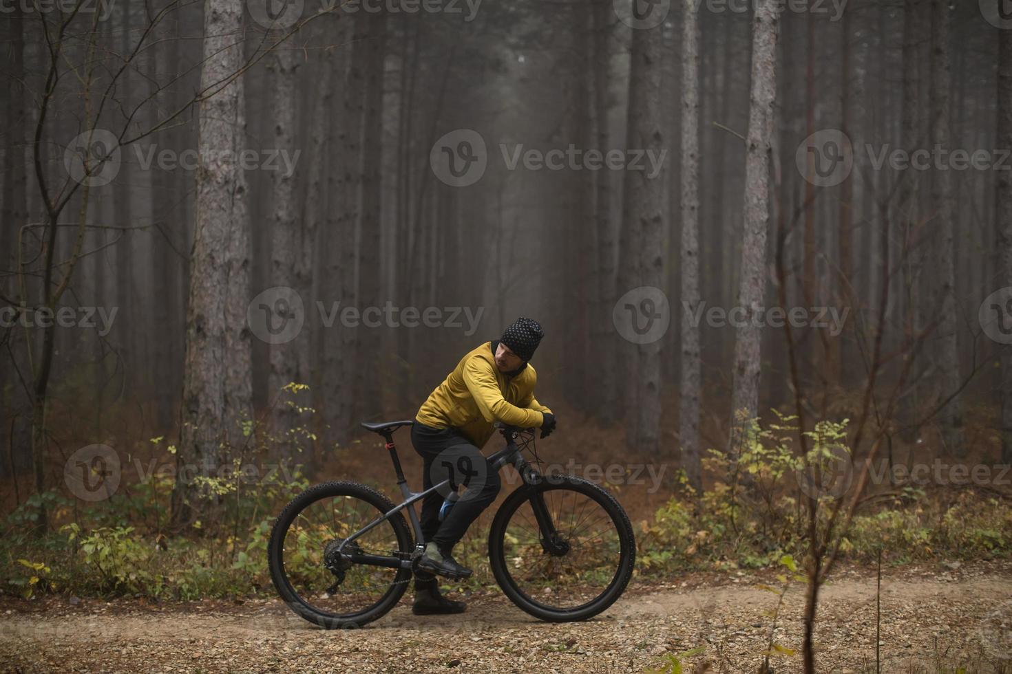 giovane uomo assunzione un' freno durante bike attraverso autunno foresta foto