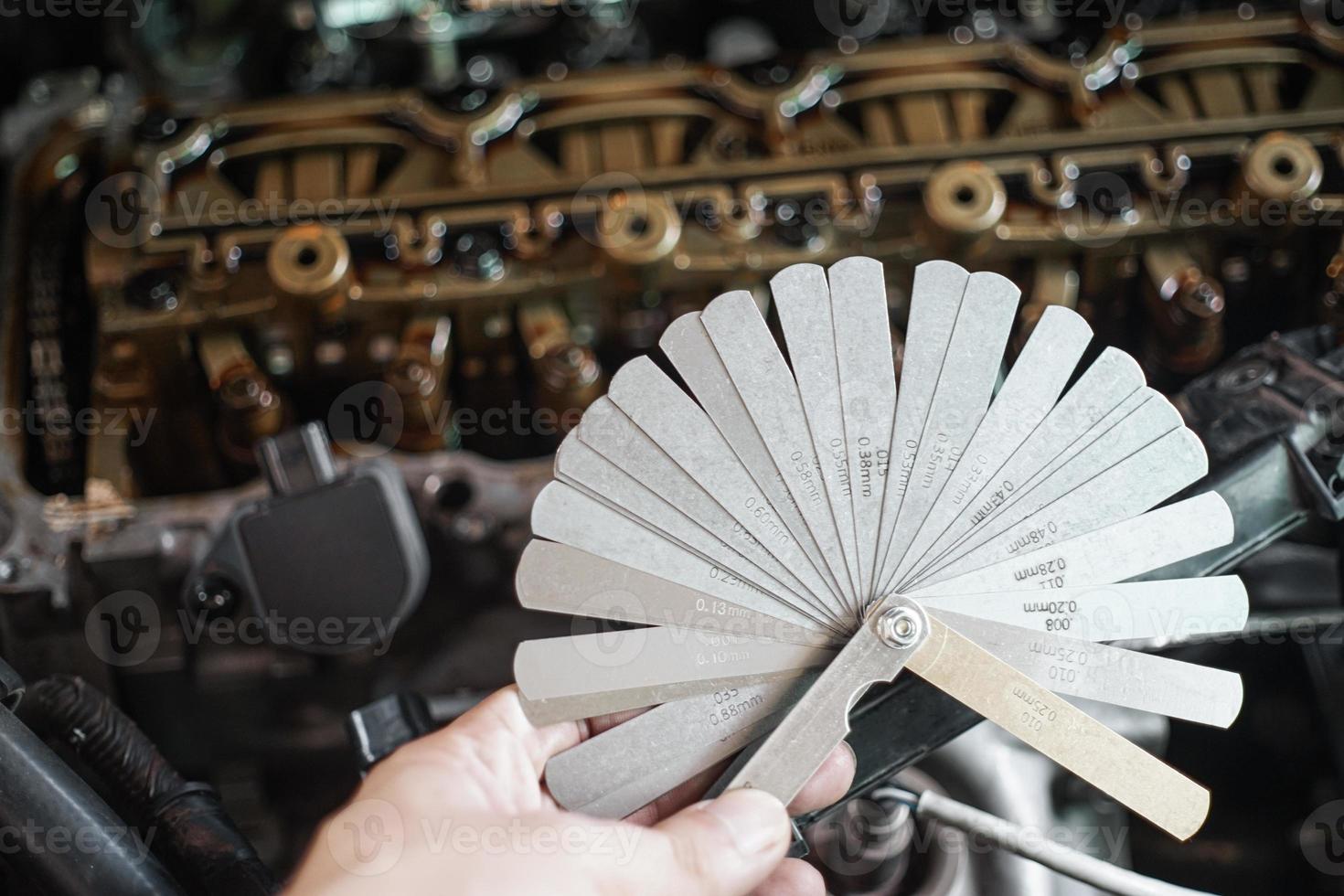 auto meccanico utilizzando tastatore valutare impostato il auto valvola. misurazione valvola autorizzazione con punteria tastatore valutare impostato foto