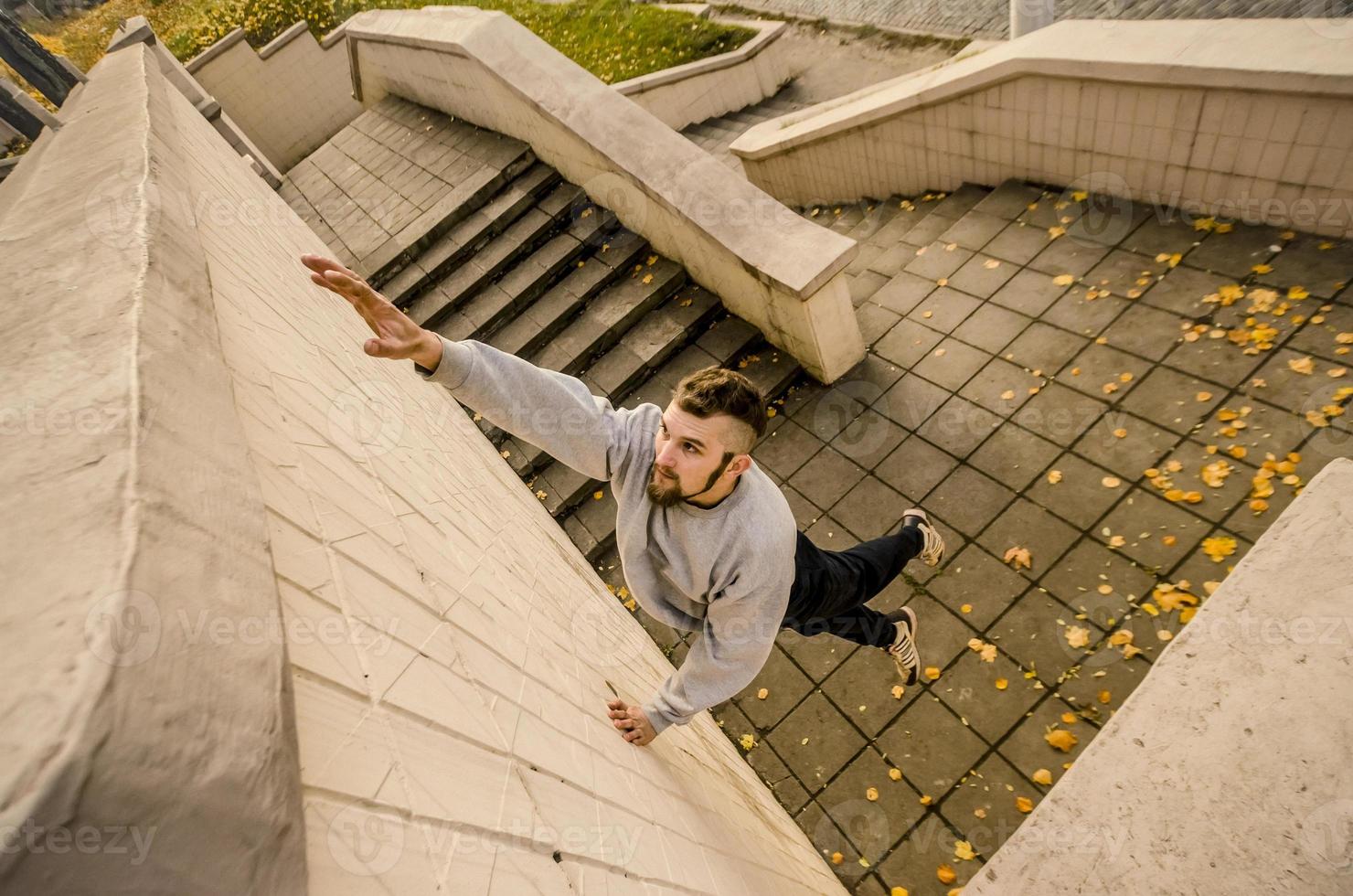 un' giovane tipo supera ostacoli, arrampicata su calcestruzzo muri. il atleta pratiche parkour, formazione nel strada condizioni. il concetto di gli sport sottoculture tra gioventù foto