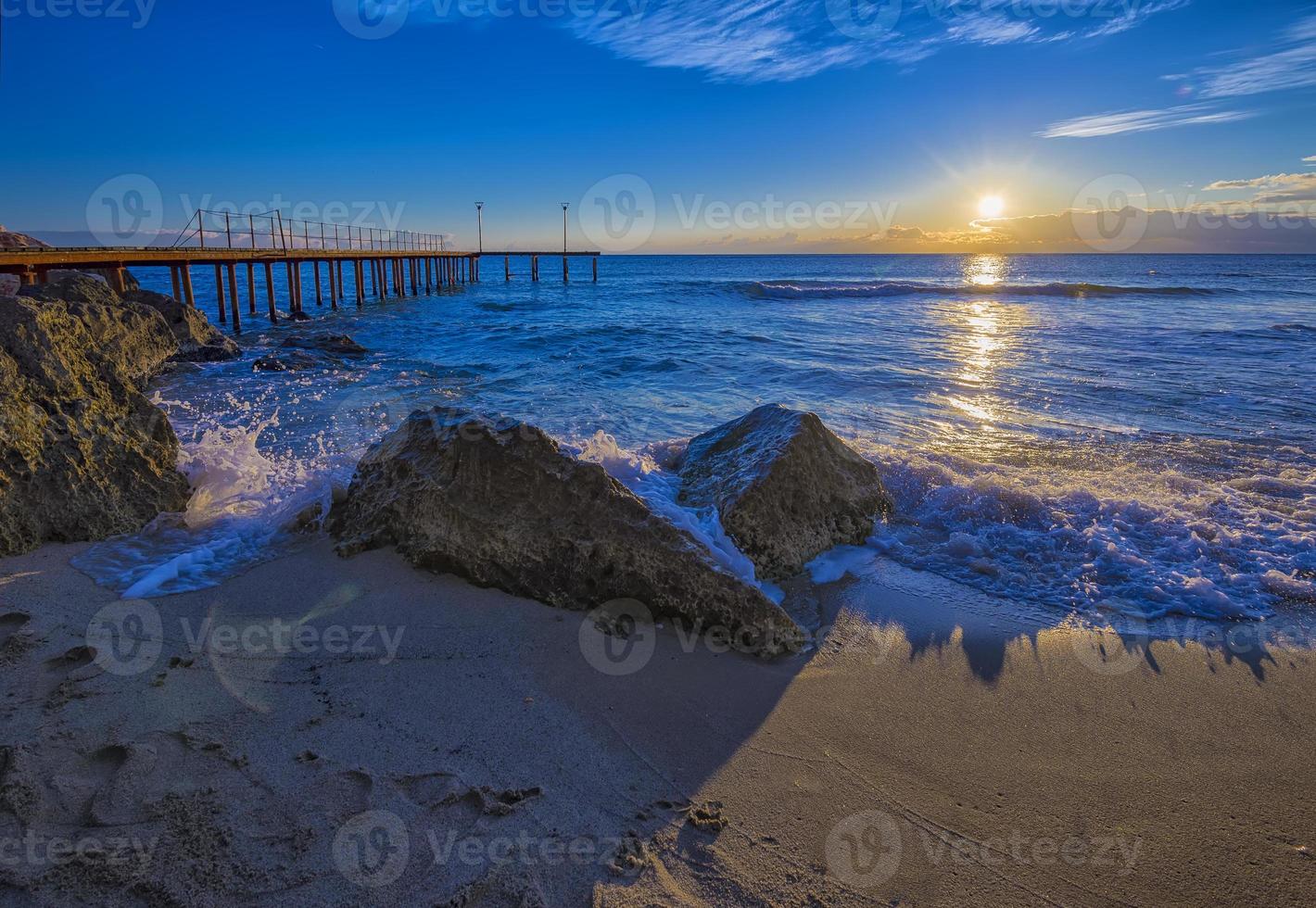 Alba al di sopra di il mare con onda spruzzi su il rocce. foto