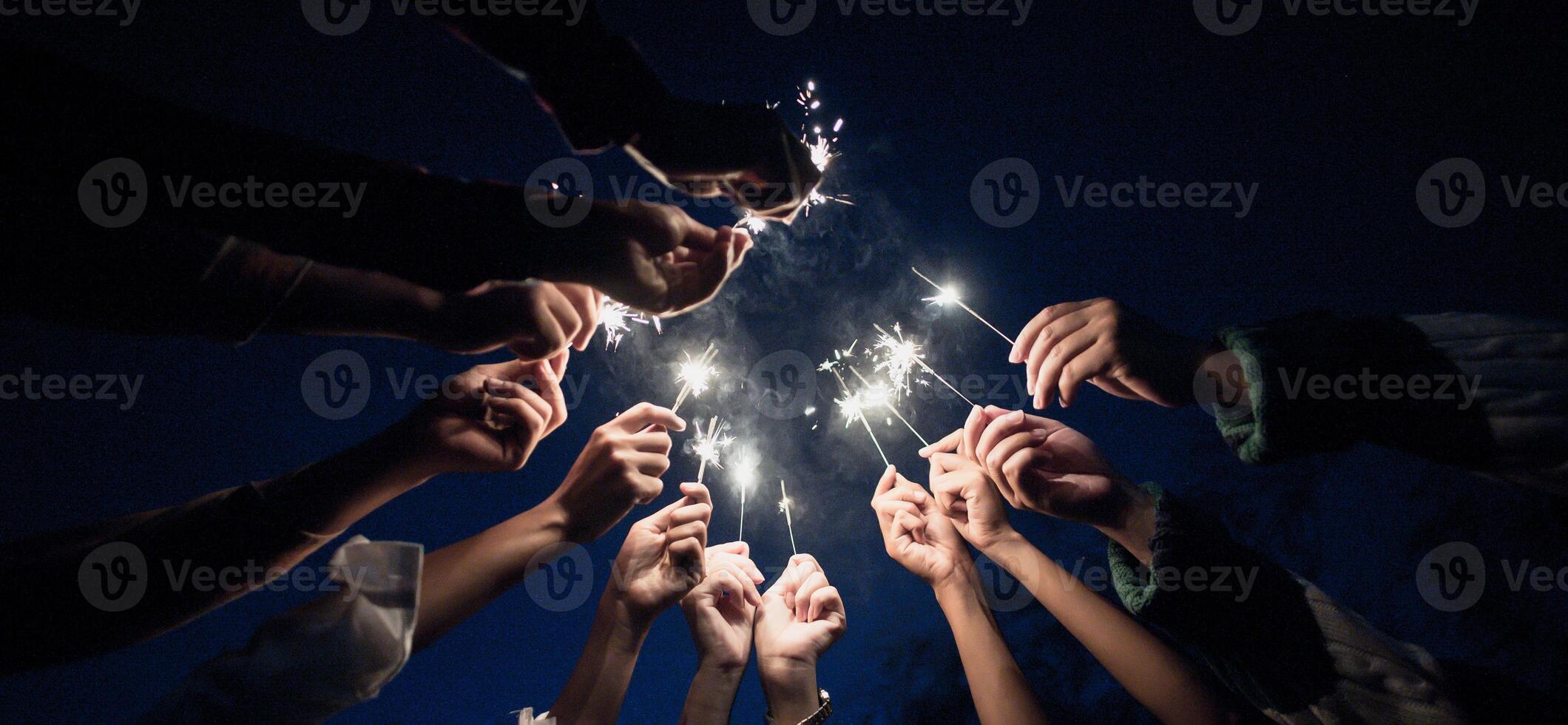 gruppo di giovane amici godere con ardente sparkler nel mani insieme foto