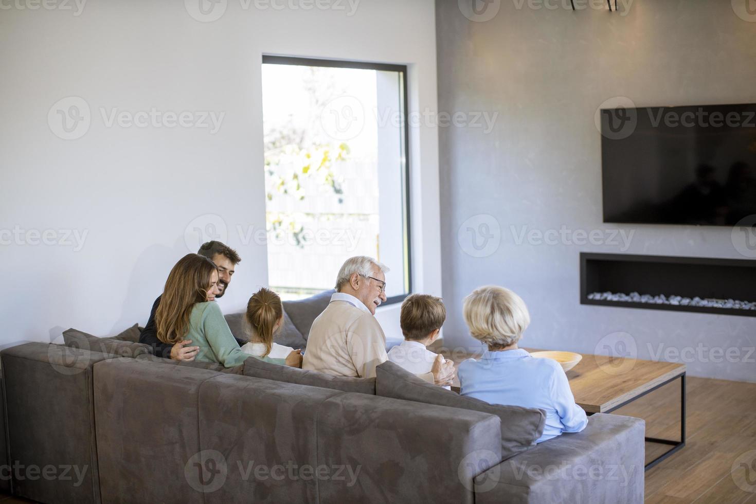 Multi generazione famiglia seduta insieme su il divano a casa e Guardando tv foto