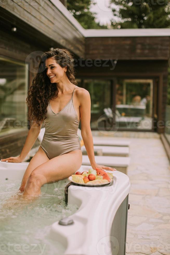 giovane donna godendo nel all'aperto caldo vasca su vacanza foto