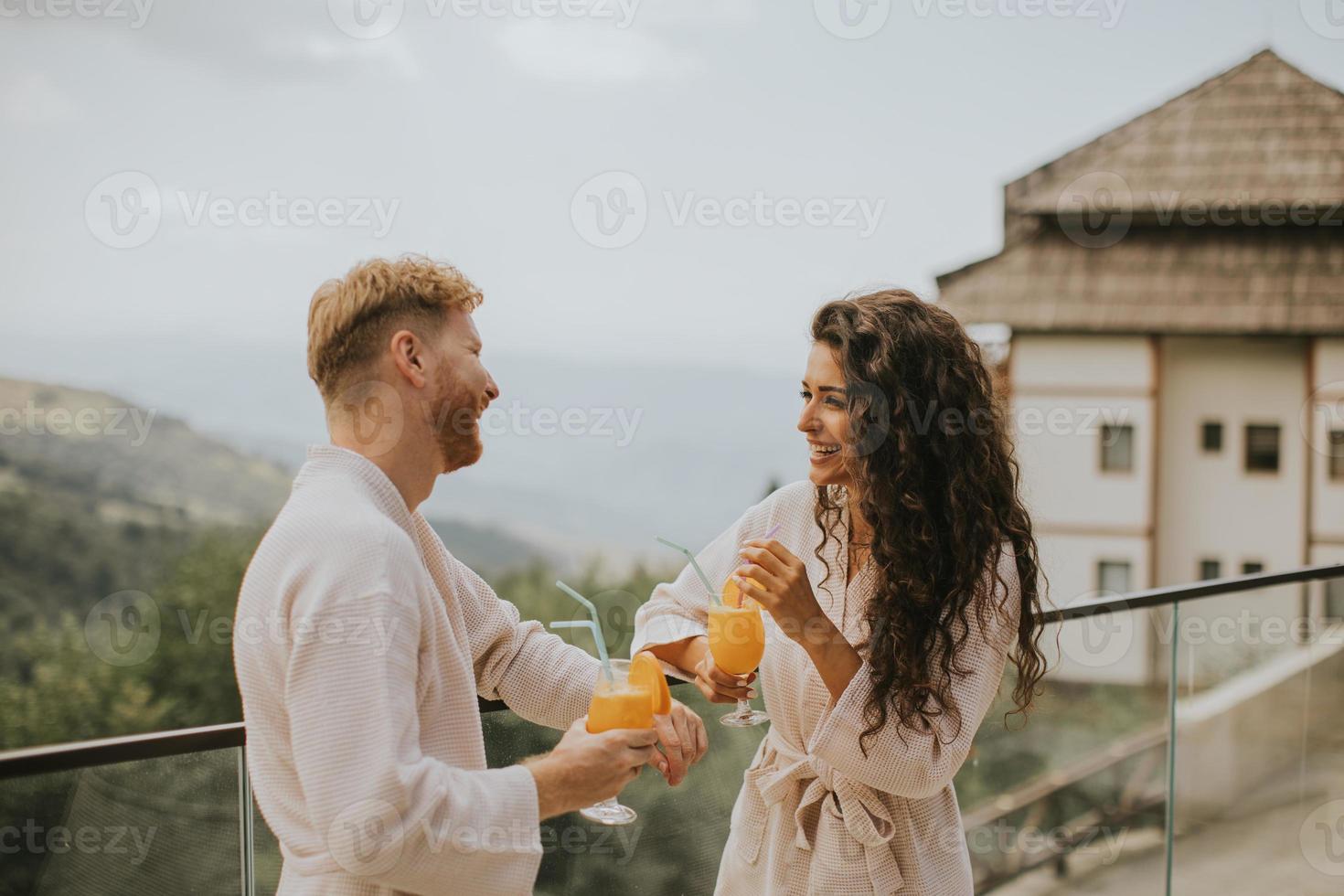 giovane coppia rilassante su il all'aperto terrazza e potabile fresco arancia succo foto