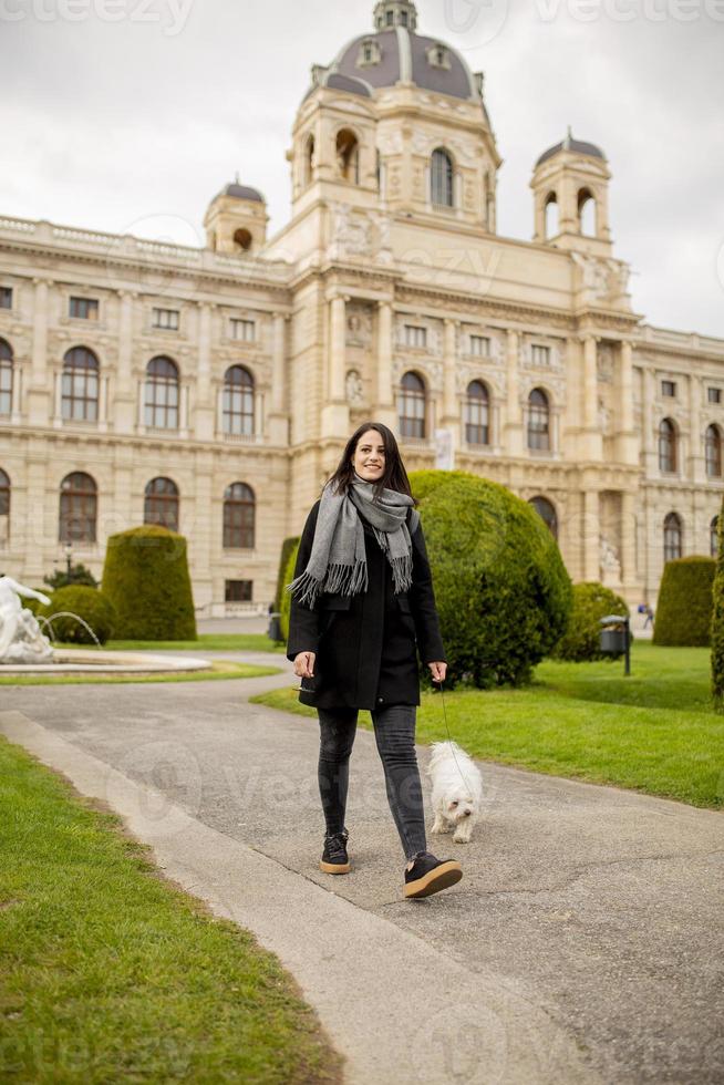 bellissimo contento giovane donna con carino piccolo cane cucciolo avere divertimento su strada foto