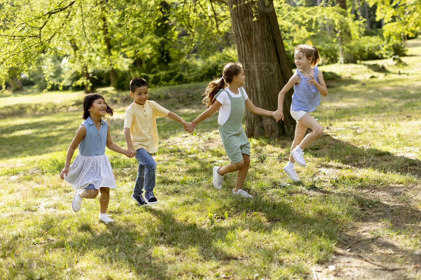 gruppo di asiatico e caucasico bambini avendo divertimento nel il parco foto