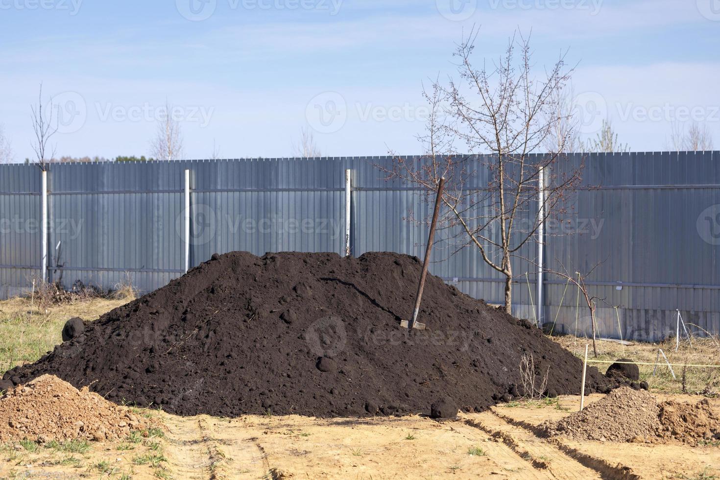 mucchio di nero suolo e un' vanga nel un' giardino foto