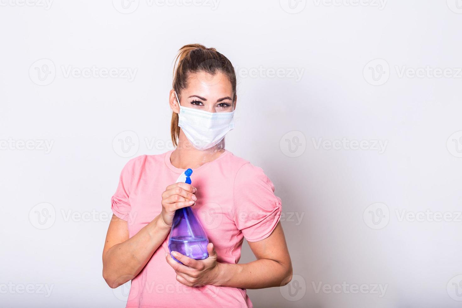 donna con protettivo facciale maschera e disinfettante spray bottiglia . lei aspersione disinfettante e pulizia il bicchiere. restare sicuro. foto