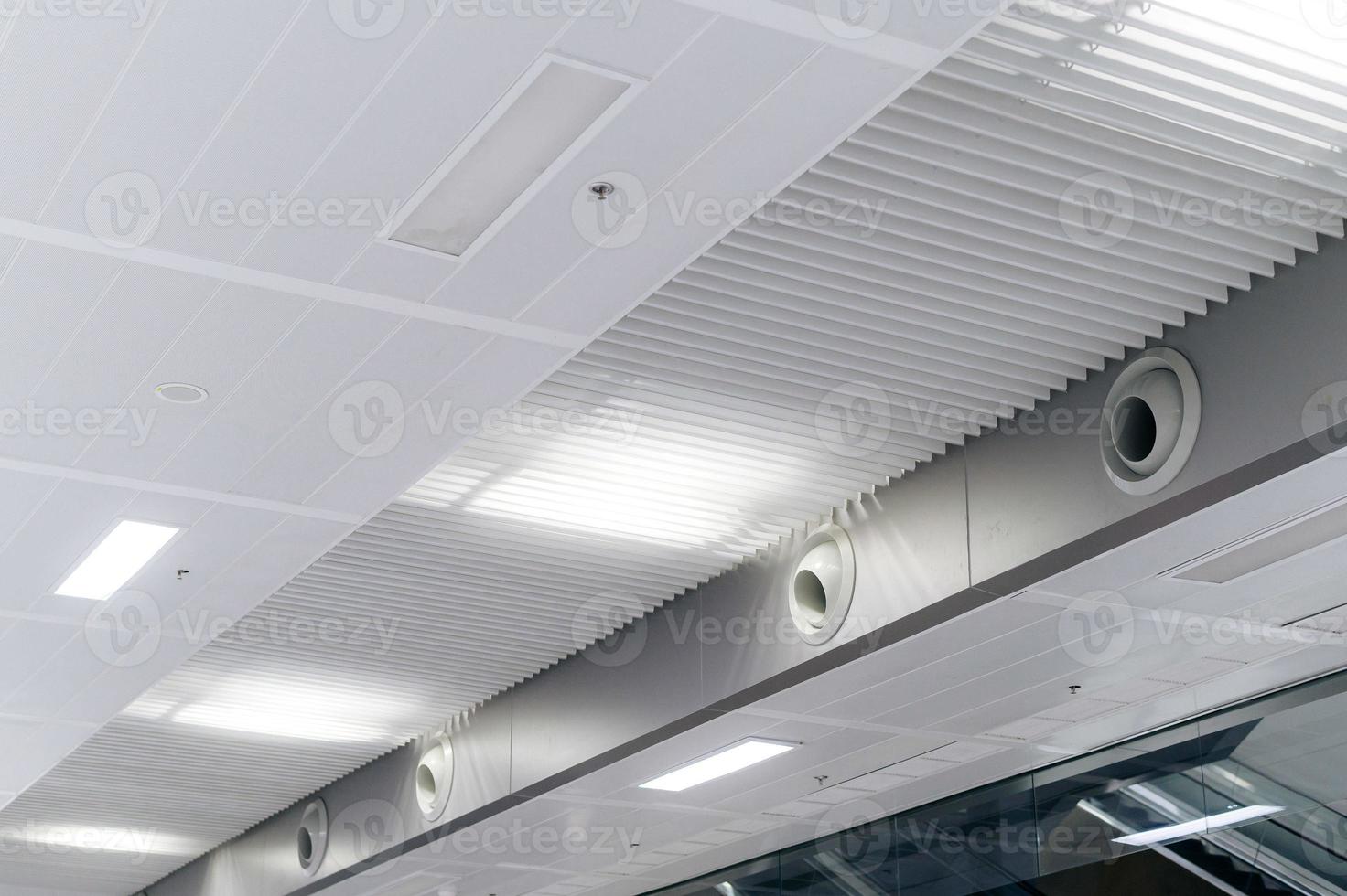 soffitto montato cassetta genere aria condizionatore e moderno lampada leggero su bianca soffitto. condotto aria condizionatore per casa o ufficio foto