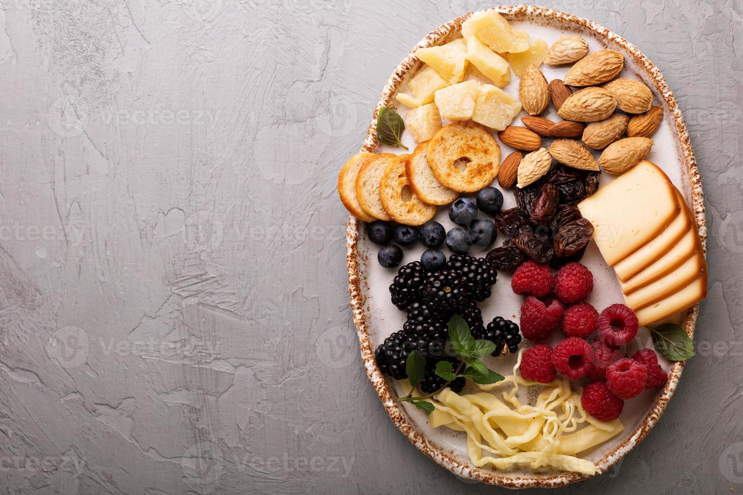 formaggio piatto con noccioline e frutti di bosco foto