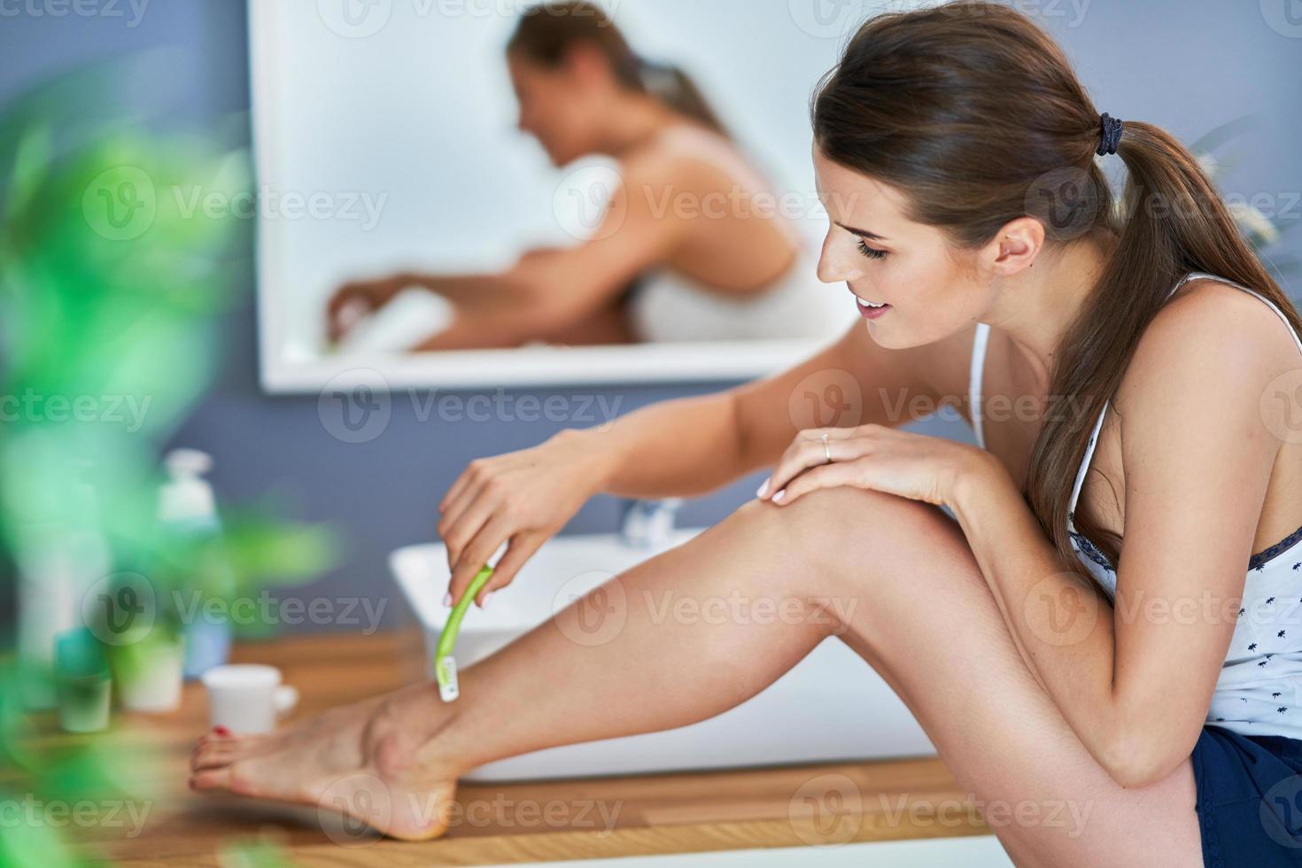 bellissimo brunetta donna rasatura gambe nel il bagno foto