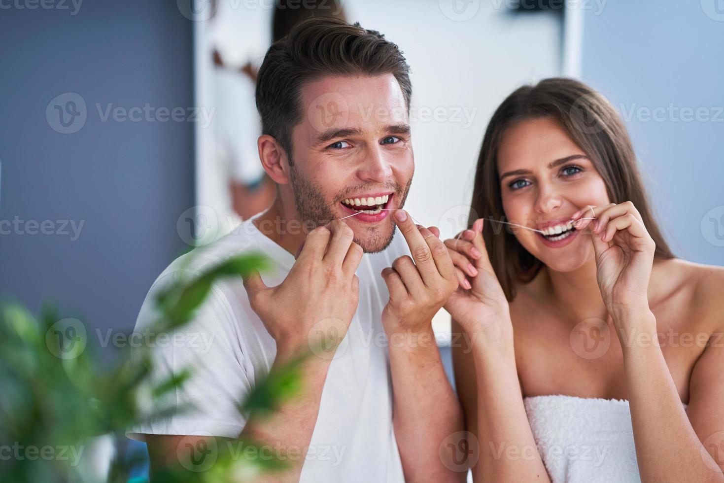 ritratto di contento giovane coppia filo interdentale denti nel il bagno foto