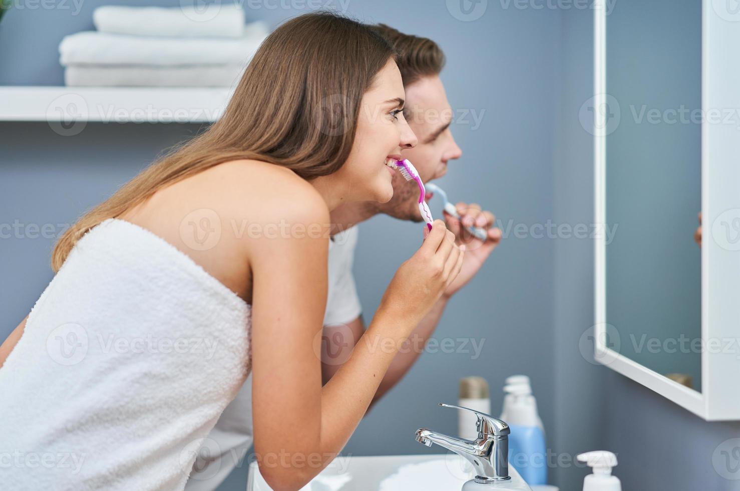 ritratto di contento giovane coppia spazzolatura denti nel il bagno foto