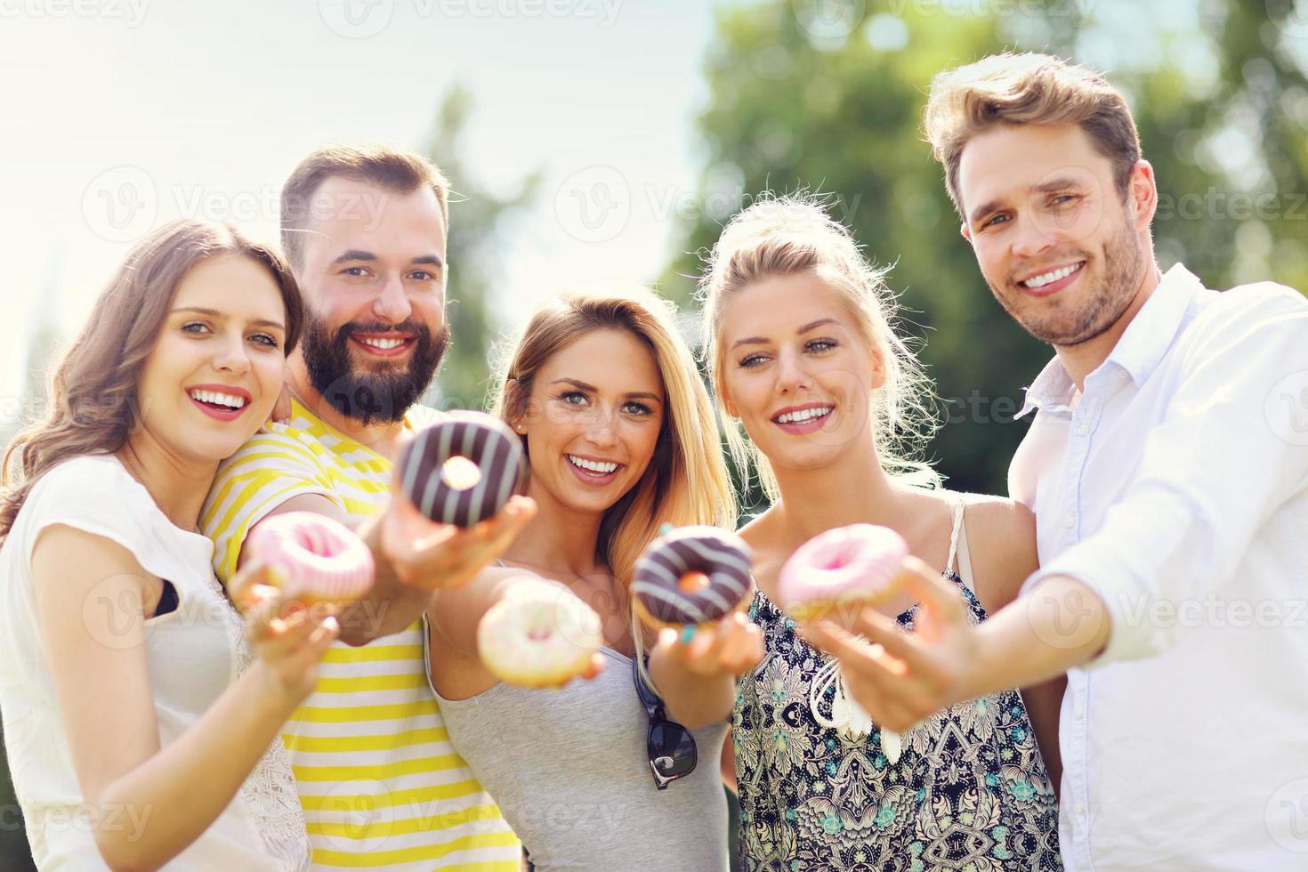 gruppo di amici mangiare ciambelle all'aperto foto