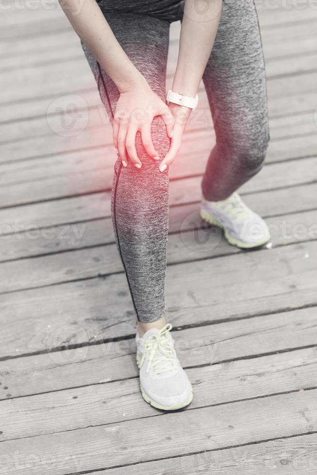 femmina atleta corridore toccante ginocchio nel dolore all'aperto foto