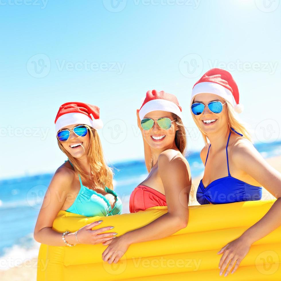 gruppo di ragazze nel Babbo Natale cappelli avendo divertimento su il spiaggia foto