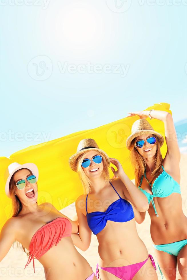 gruppo di donne avendo divertimento con materasso su il spiaggia foto