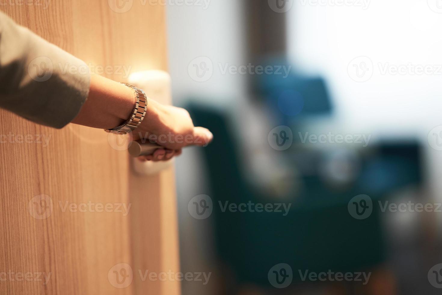 porta semiaperta di una camera d'albergo con la mano foto