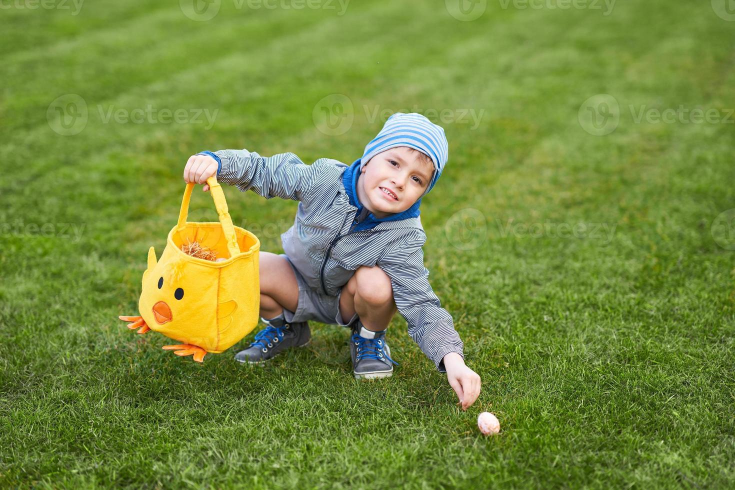 poco ragazzo indossare protettivo maschera a caccia per Pasqua uovo nel primavera giardino. foto