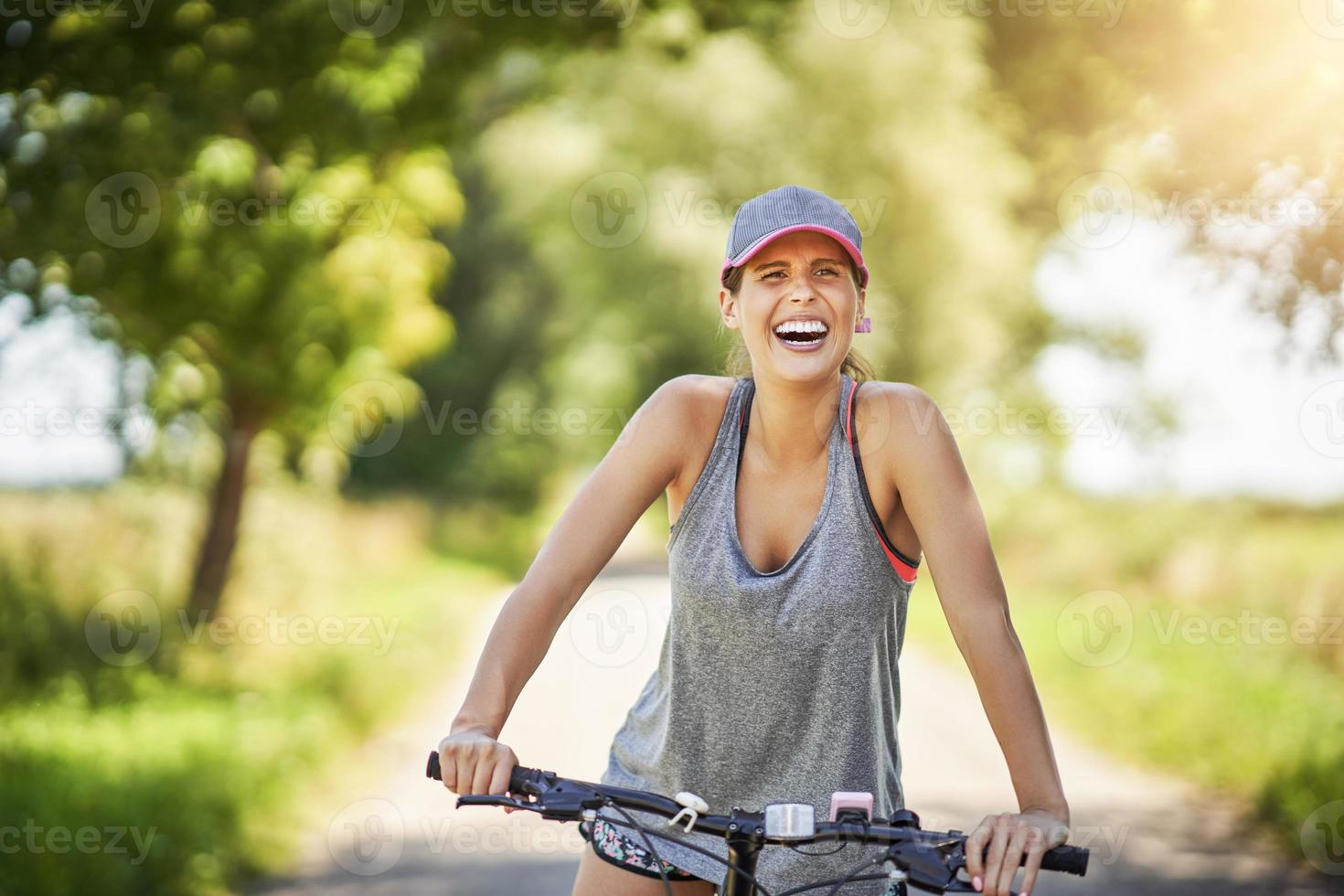 giovane contento donna su un' bicicletta nel campagna foto