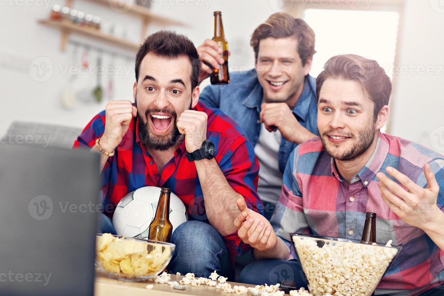 contento maschio amici applauso e Guardando gli sport su tv foto