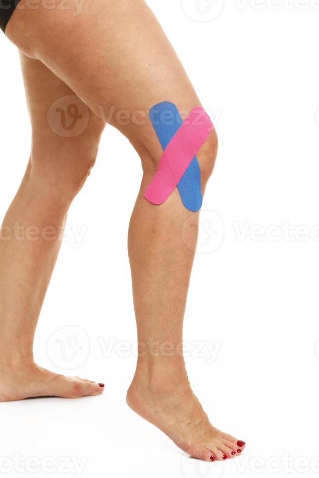 immagine mostrando speciale fisio nastro mettere su ferito ginocchio al di sopra di bianca sfondo foto