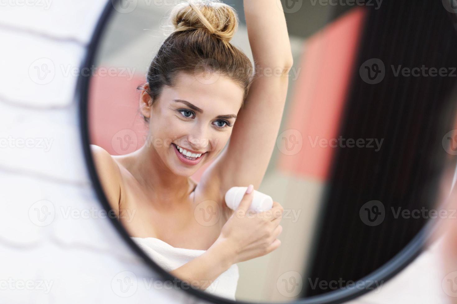 giovane donna utilizzando deodorante nel bagno foto