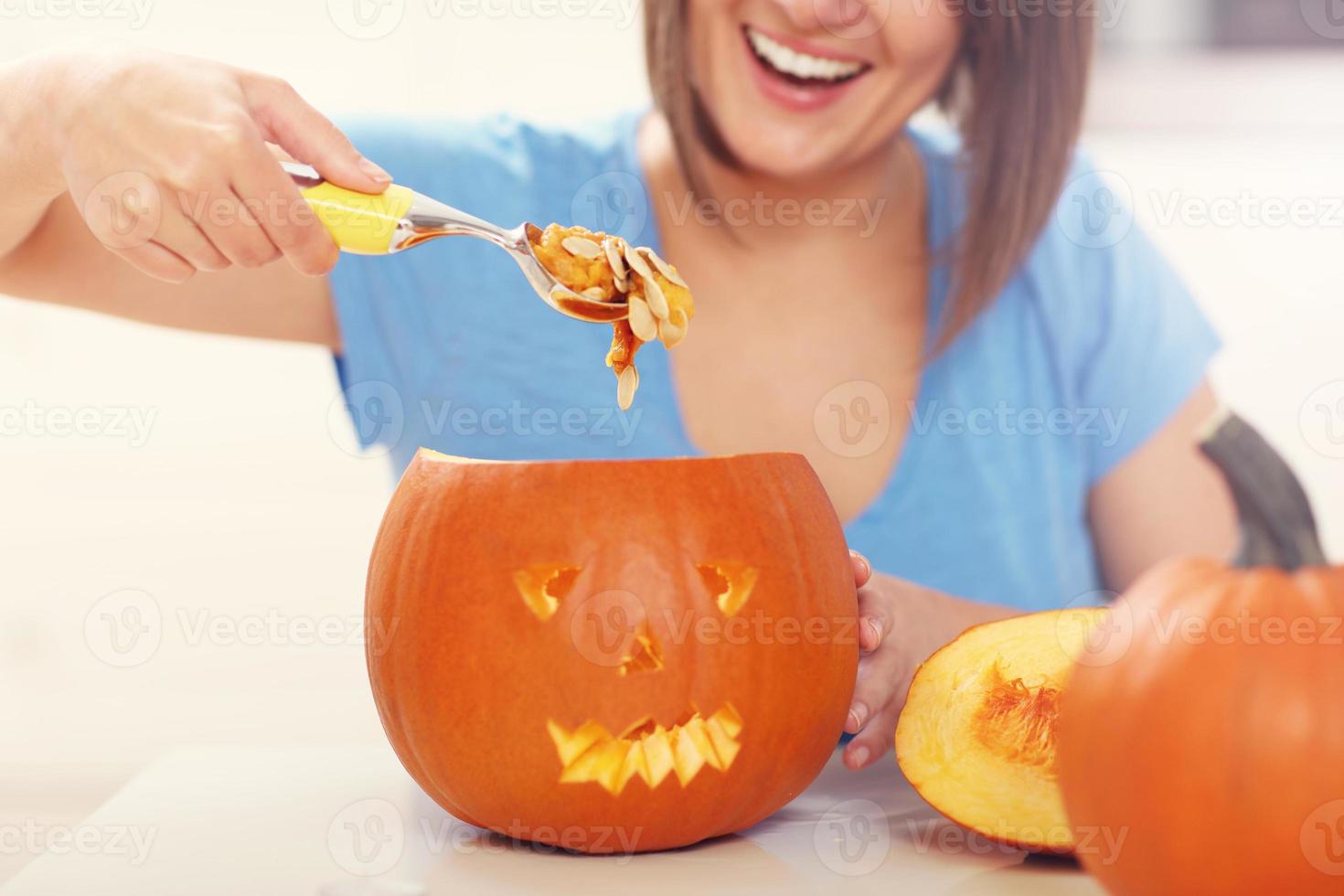 giovane donna fabbricazione jack-o-lanterna nel il cucina foto