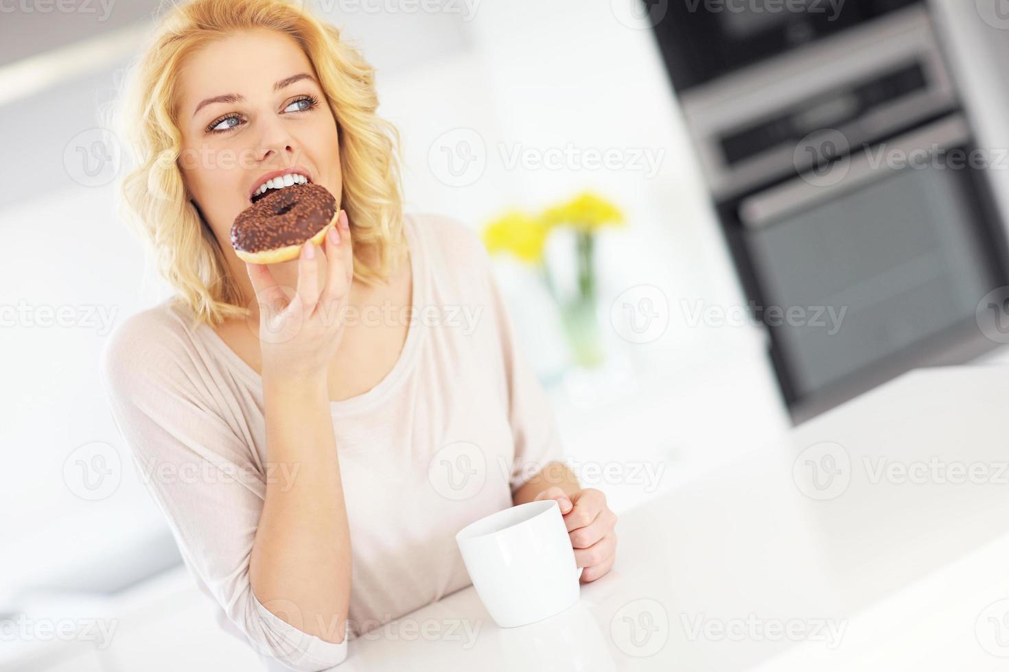 giovane donna con ciambella e caffè nel il cucina foto