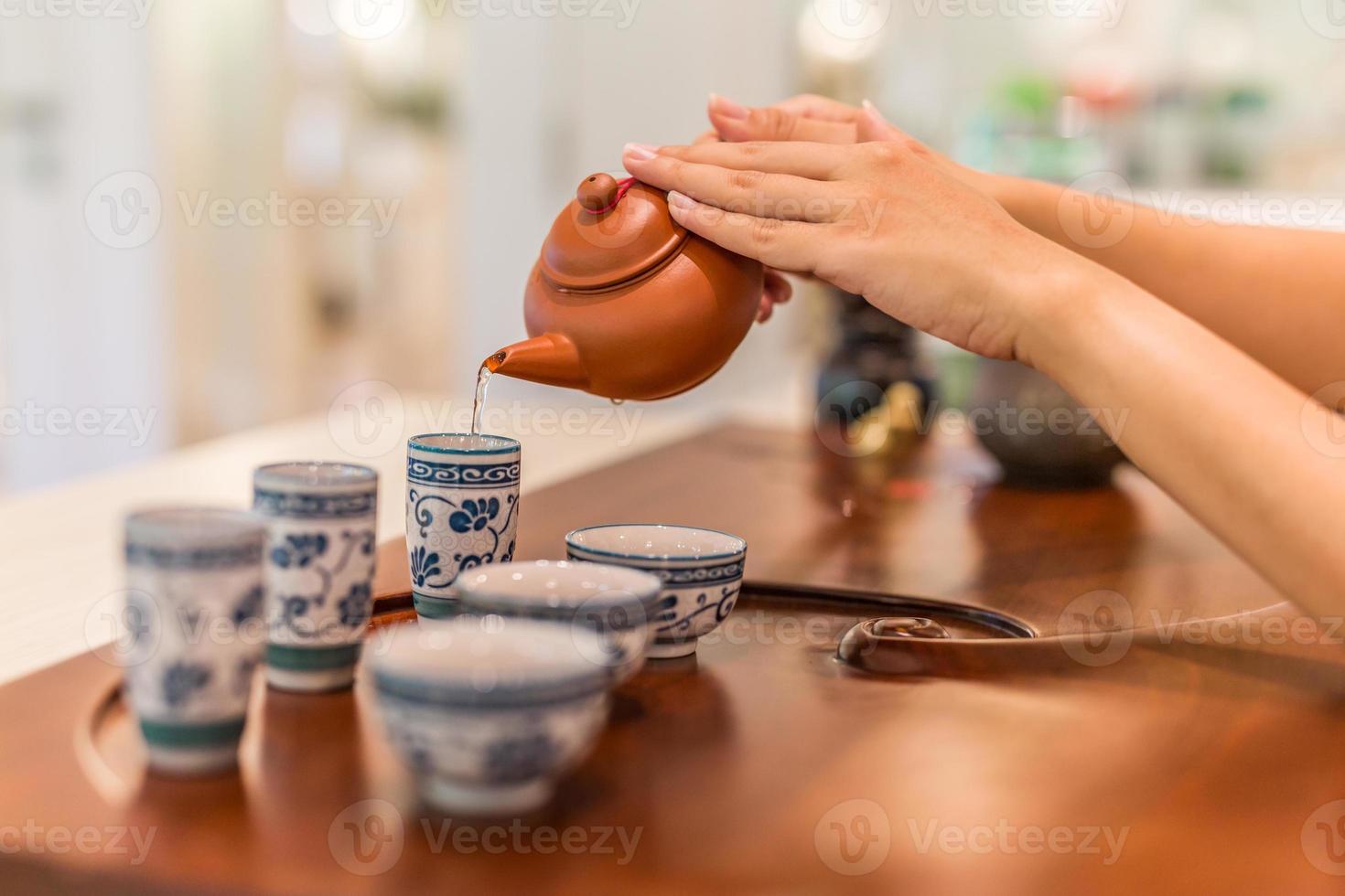 tè è versato in il tazza avvicinamento. asiatico tè impostare su di legno bambù tavolo, mano delicatamente scrosciante Cinese tè foto