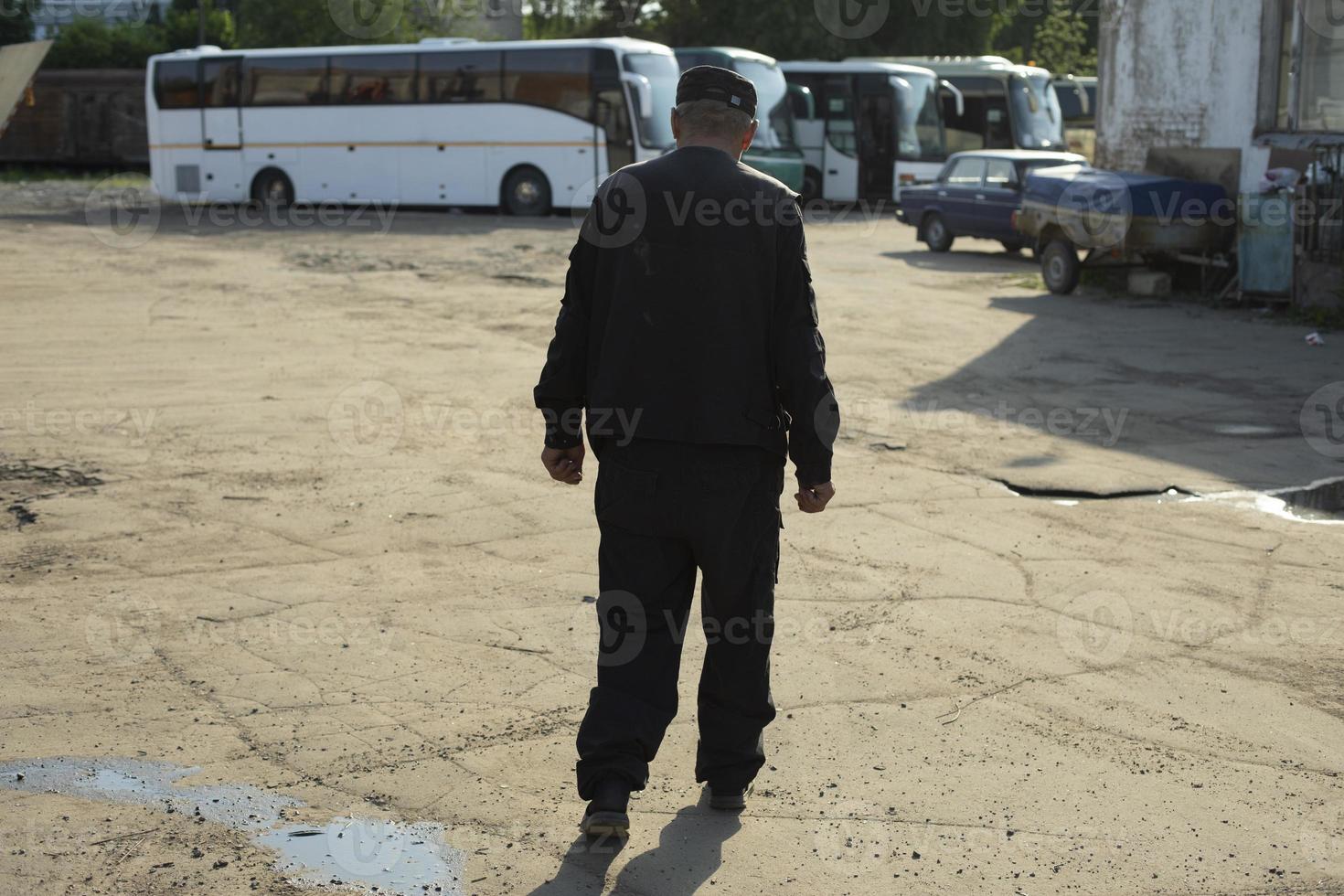 uomo passeggiate attraverso industriale la zona. autobus parcheggio. parcheggio guardia. foto