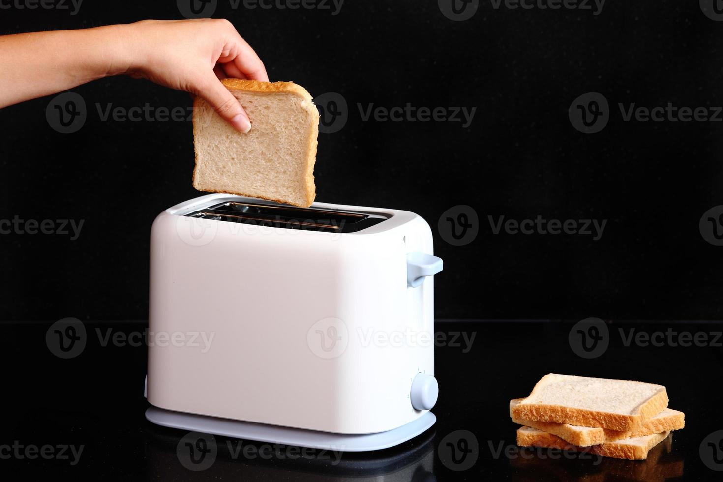 mano mettendo pane per tostapane foto