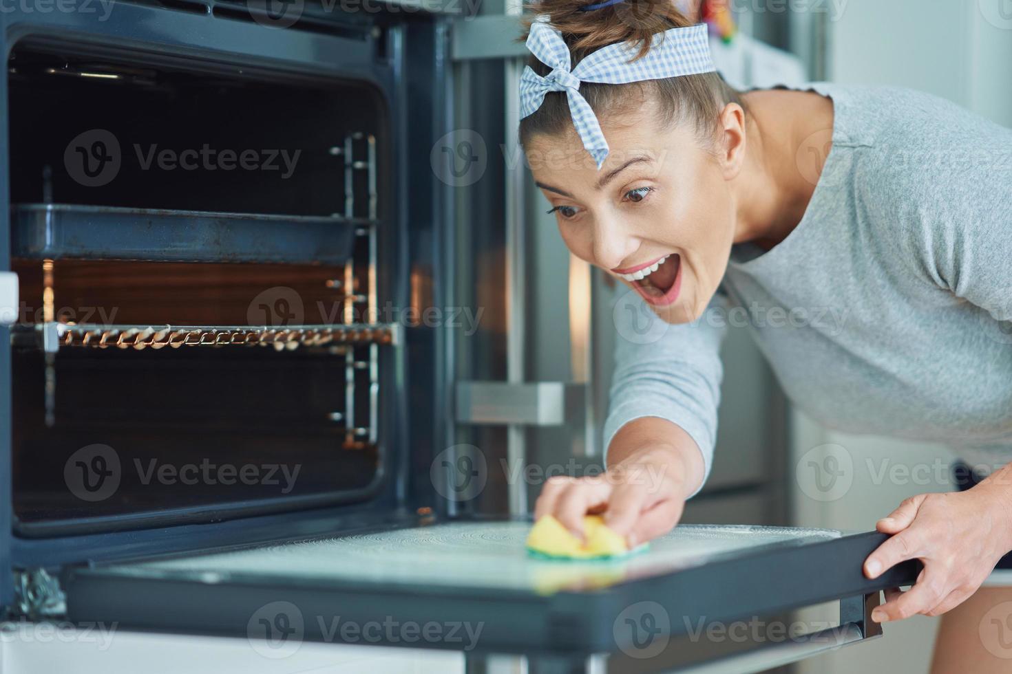 giovane donna pulizia forno nel il cucina foto