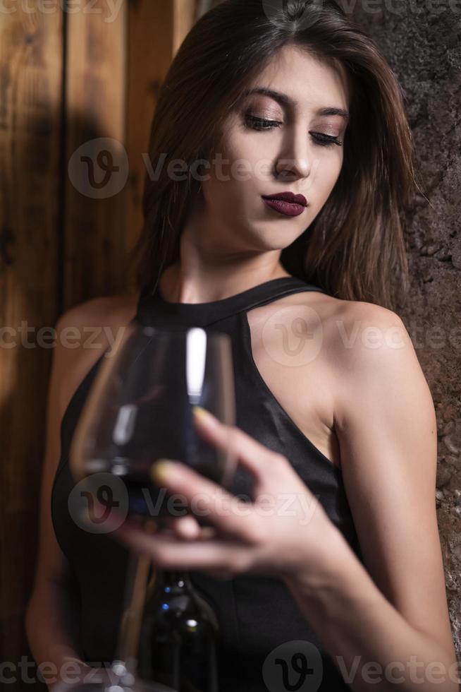 femmina alla moda modello Tenere bicchiere di vino. donna potabile vino. foto