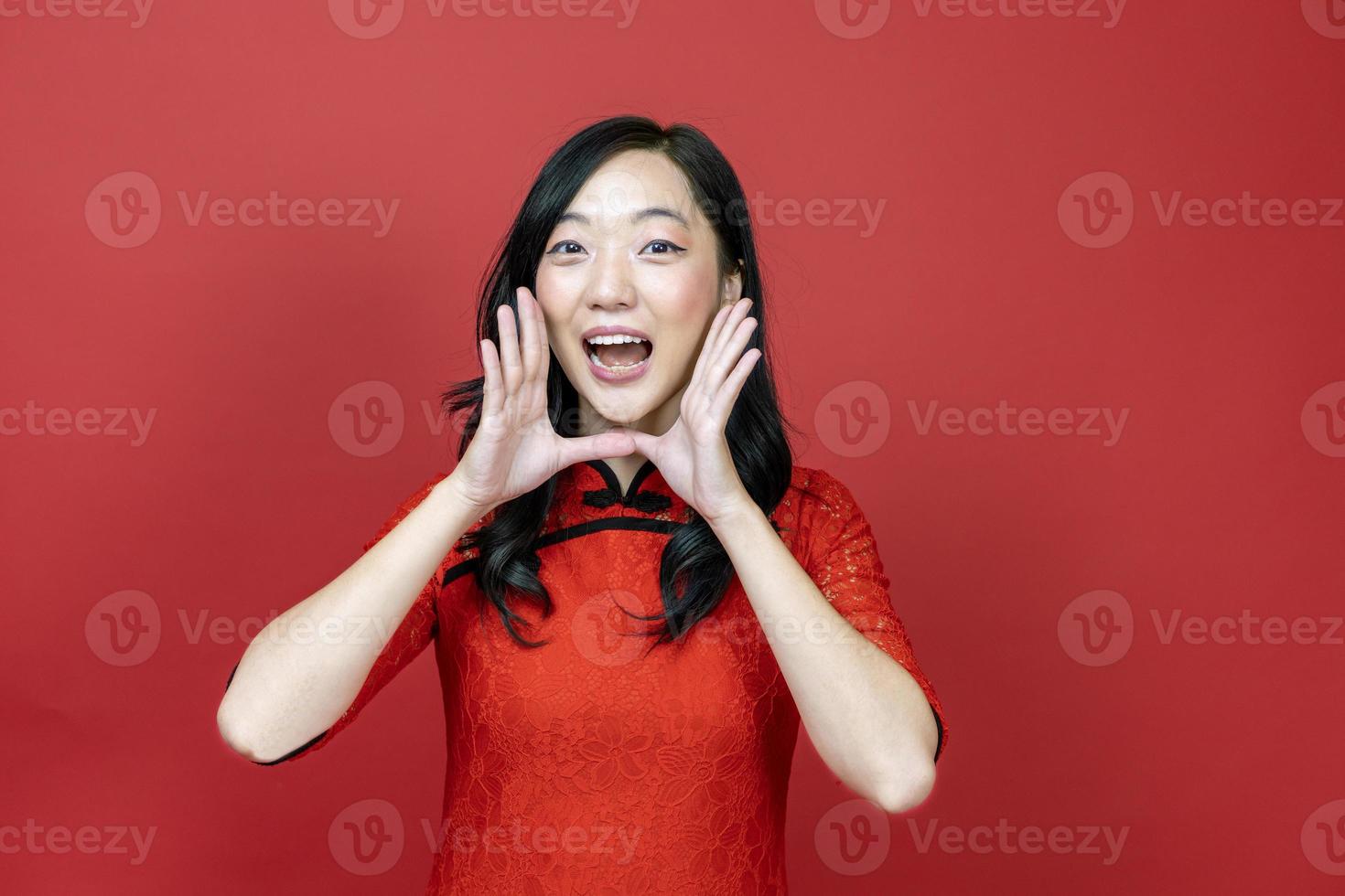 asiatico Cinese donna nel rosso cheongsam o qipao chiamata persone per desiderio il bene fortuna e prosperità nel Cinese nuovo anno celebrazione vacanza isolato su rosso sfondo foto