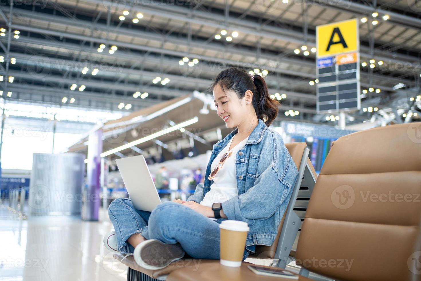attraente femmina turista Lavorando con il computer portatile nel aeroporto terminale. libero professionista alunno viaggi per attività commerciale incontro. foto