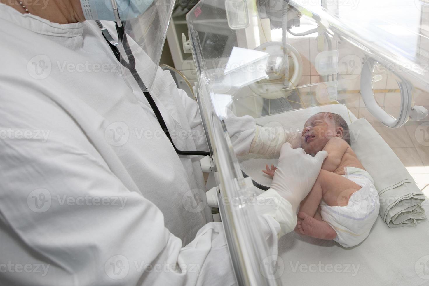 un' medico orologi al di sopra di un' precoce bambino nel il Ospedale. foto