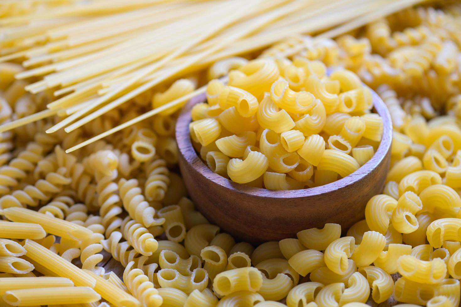 crudo maccheroni su di legno ciotola, pasta vario tipi di crudo pasta spaghetti e tagliatelle su sfondo, italiano cibo culinario concetto, collezione di diverso crudo pasta per cucinando cibo foto