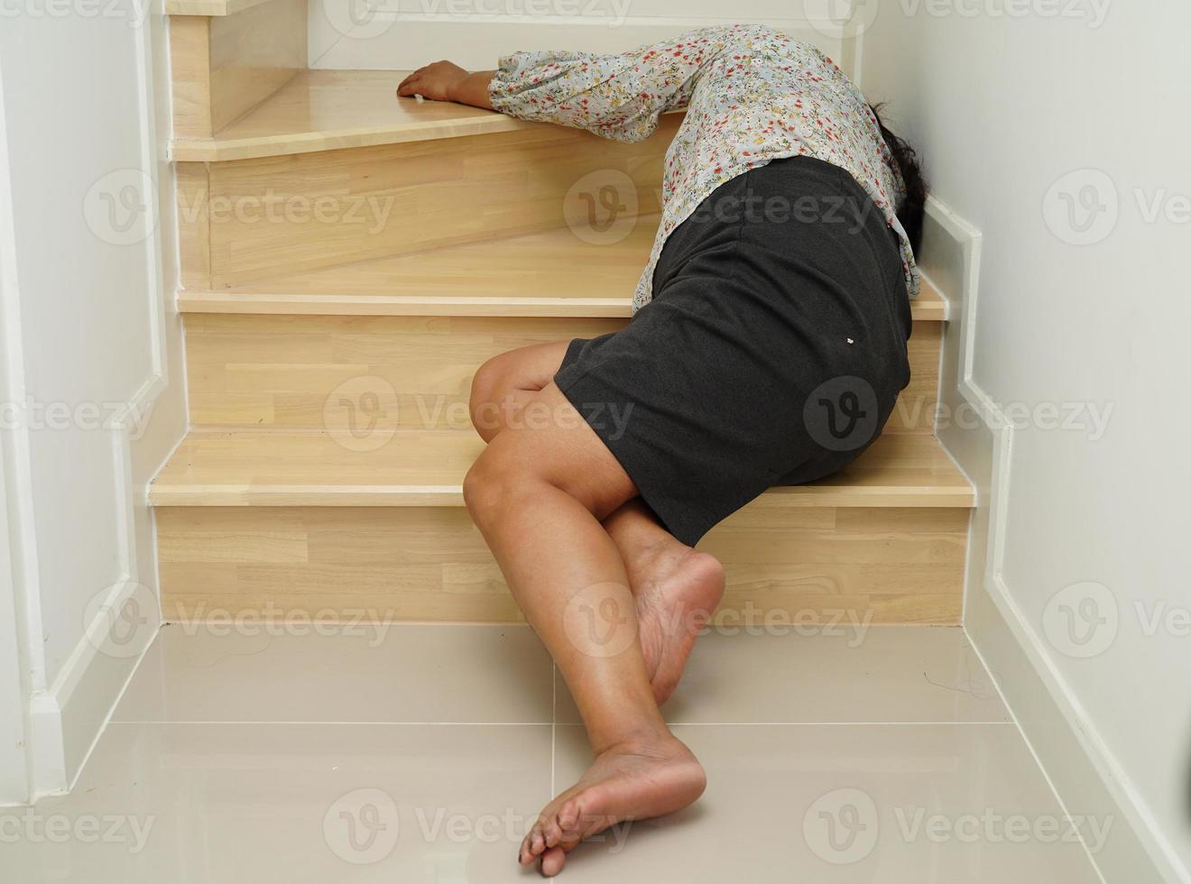 asiatico signora donna infortunio a partire dal caduta giù su scivoloso superfici le scale a casa. foto