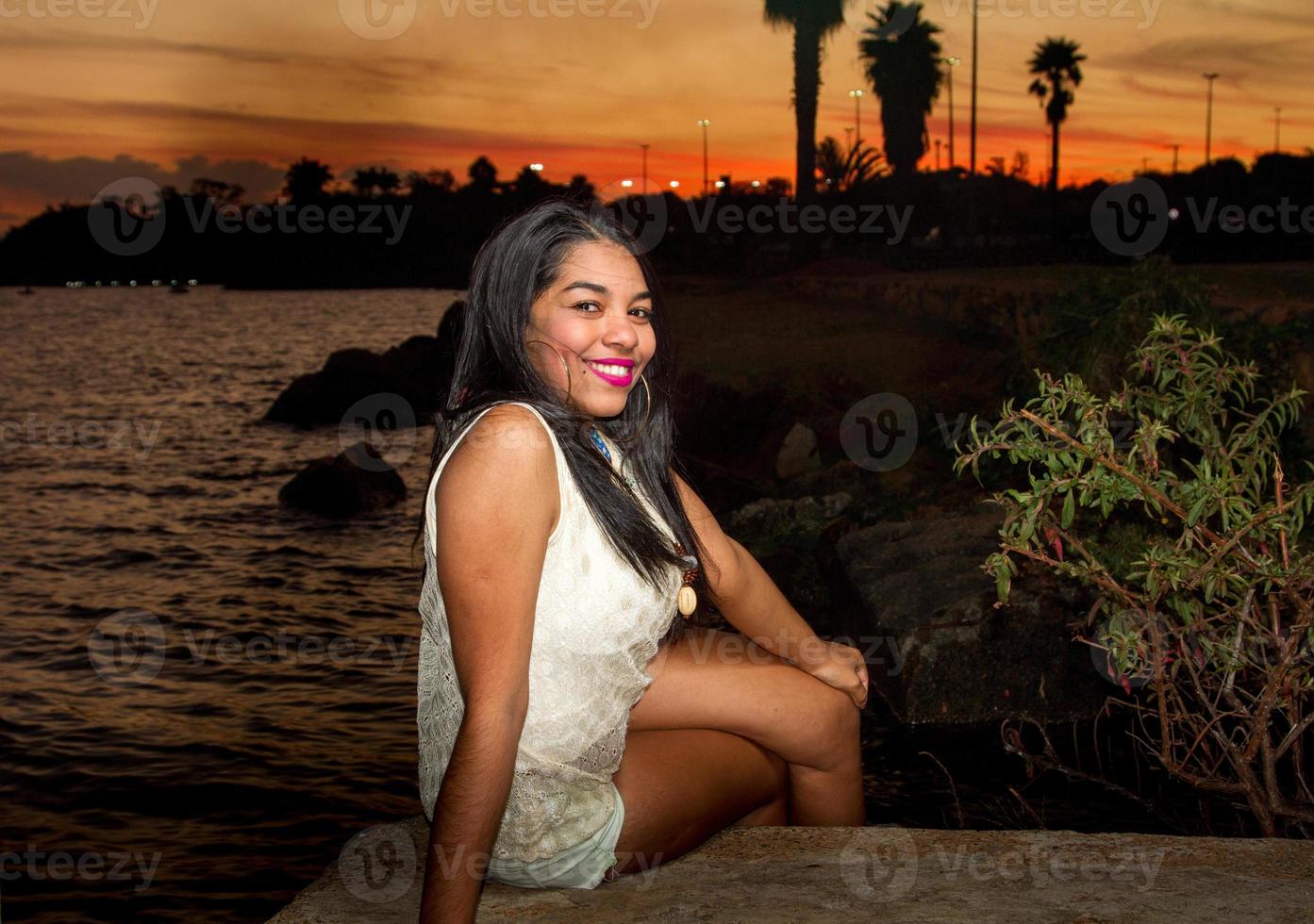 bello giovane brasiliano ragazza con un' bellissimo Sorridi a il parco a tramonto foto